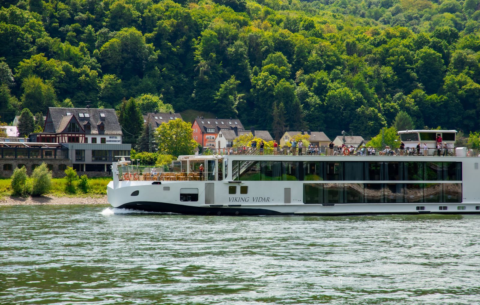 The Viking longship Viking Vidar sailing past a riverside village, the ship style you book when you get the best deal on a Viking river cruise